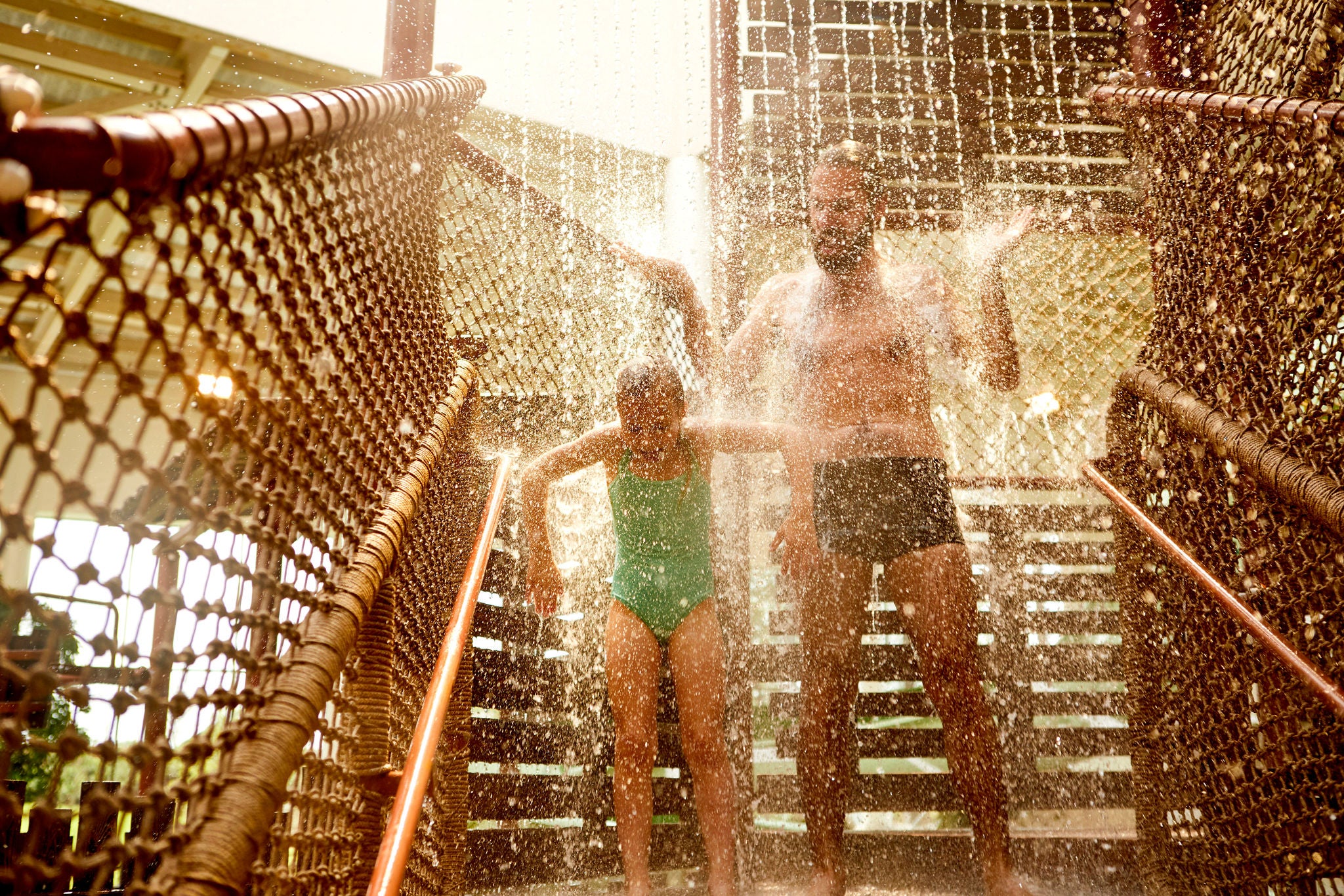 Papa en dochter lopen door een watergordijn van het Aqua Fort.
