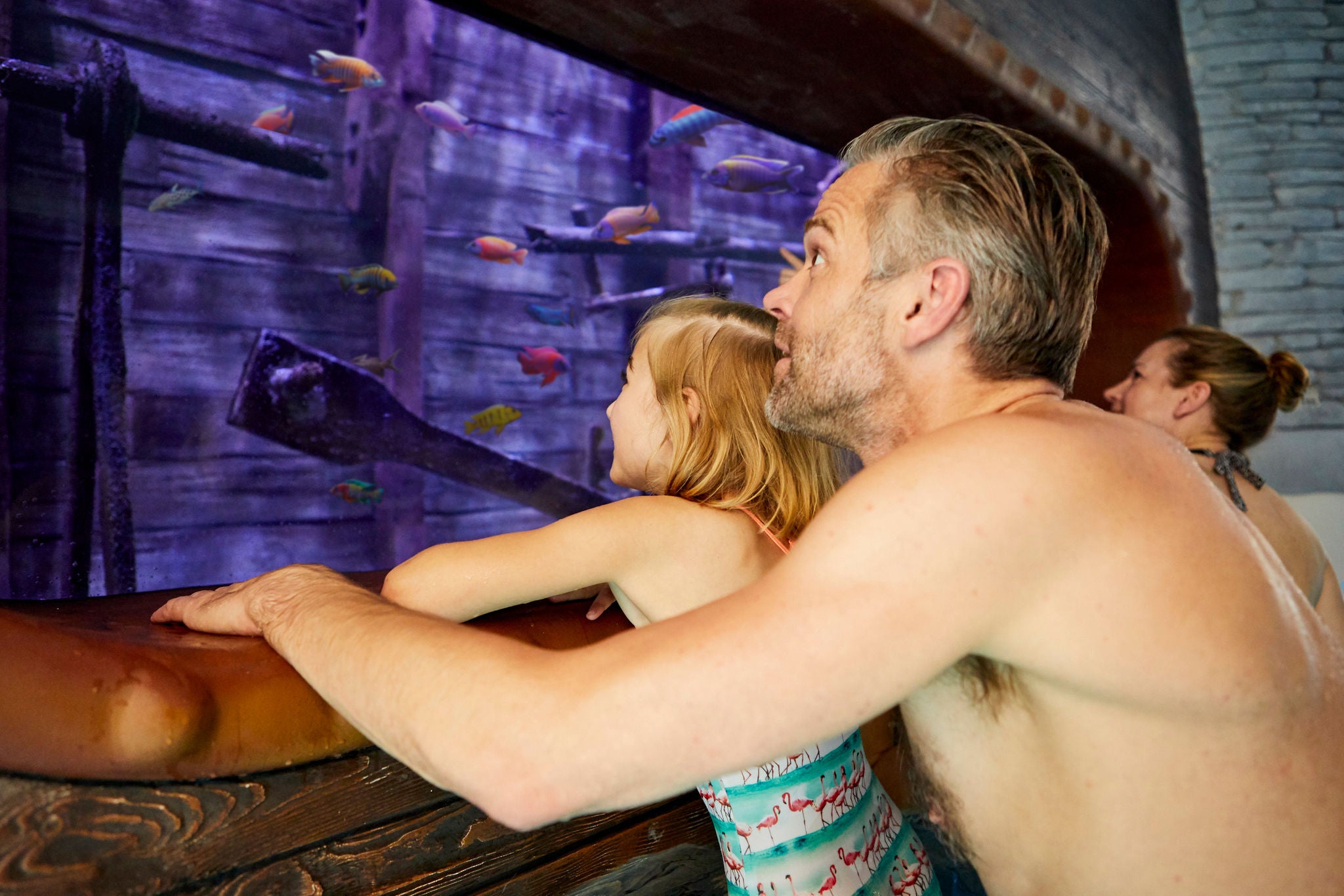 Papa kijkt samen met zijn dochter vanuit de Jungle Expedition door het raam naar de vissen van het Aquarium.