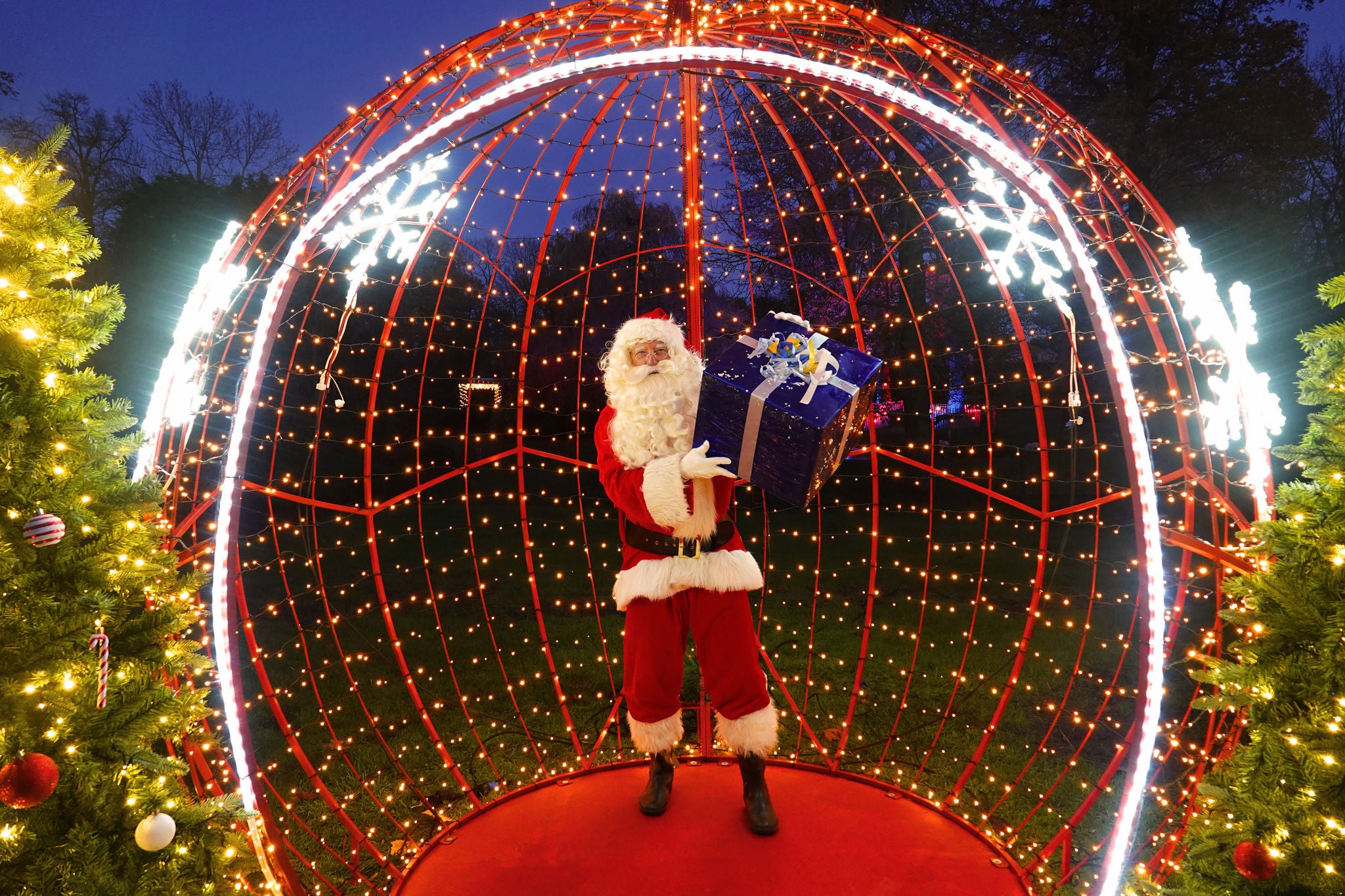 Kerstman met een cadeau in een grote, verlichte kerstbal.
