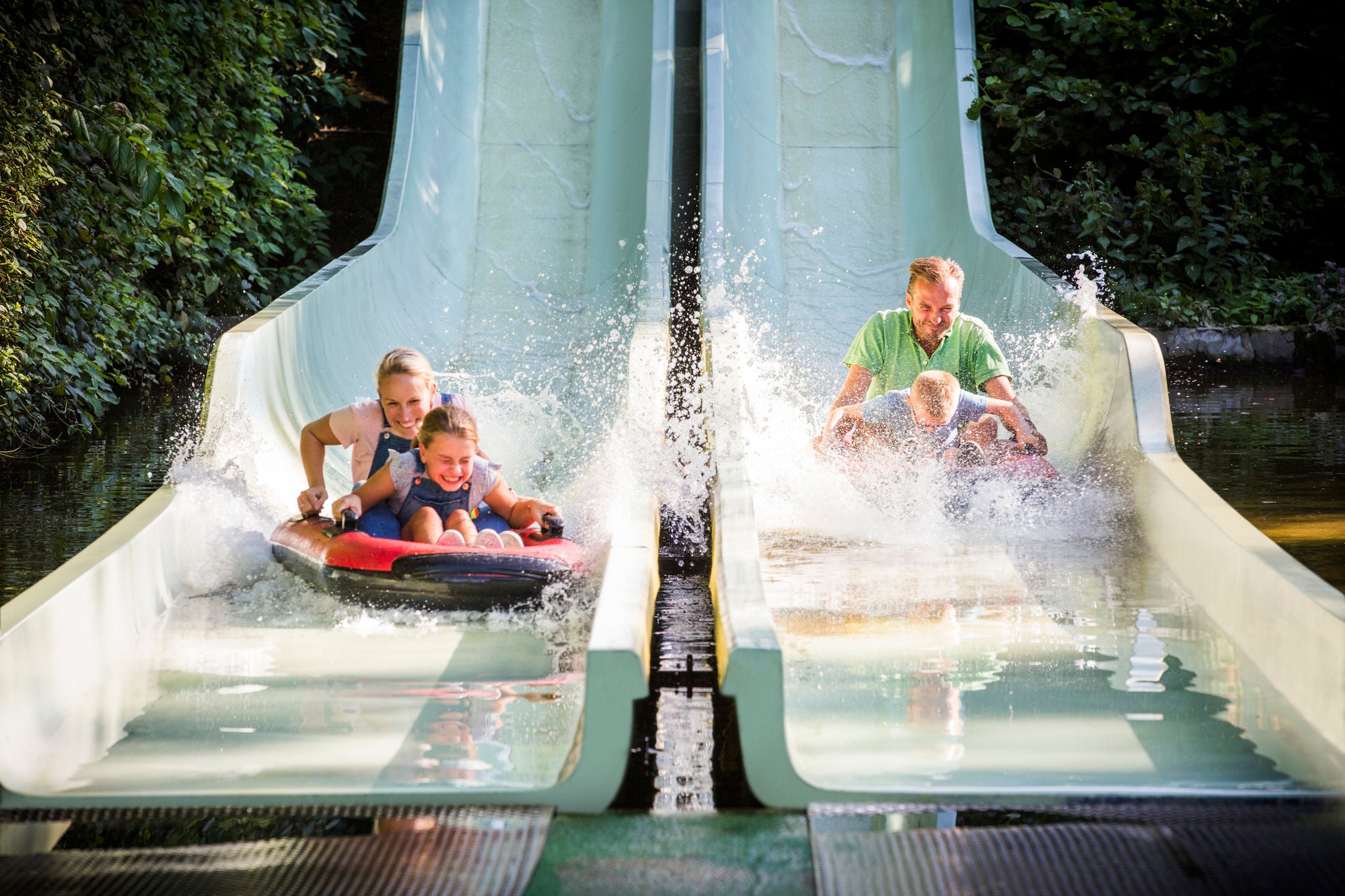 Gezin maakt een splash met hun boot onderaan de afdaling van Big Chute.