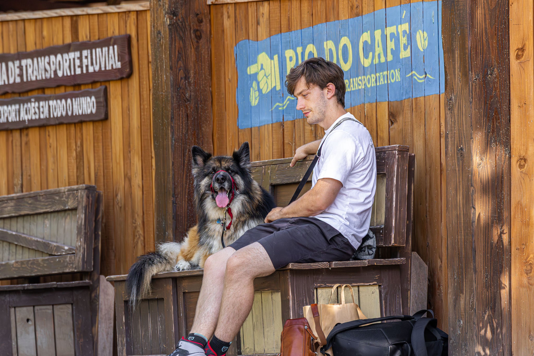Baasje zit samen met zijn hond op een bank naast Rio Do Café.