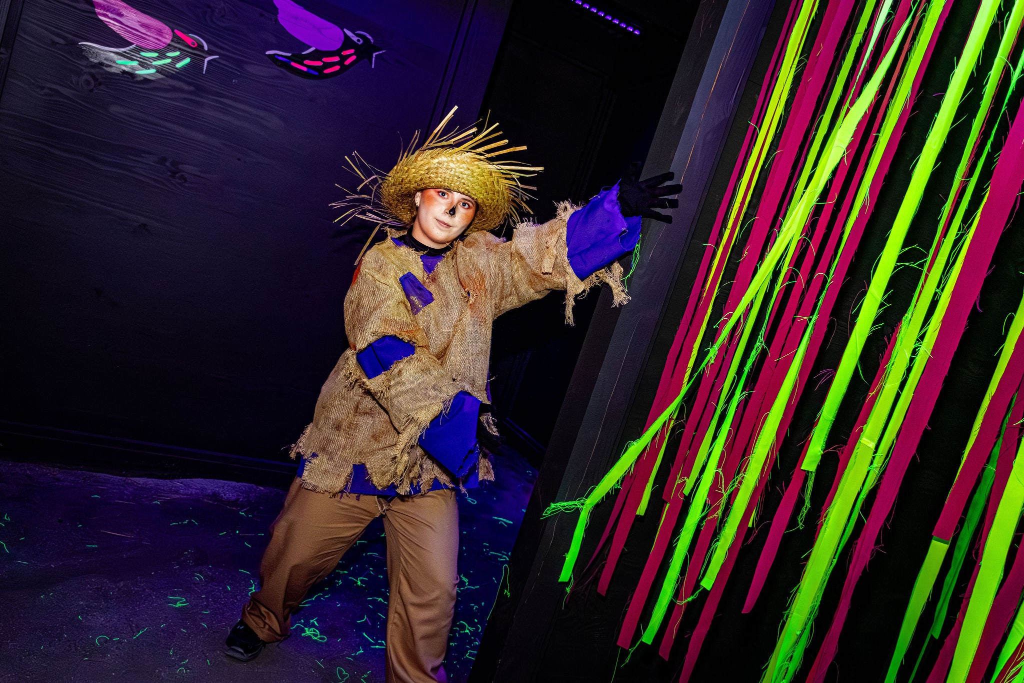 Pompoenman wijst de weg tussen de fluo slingers en fluo muurschilderijen in Pumpkin Panik.