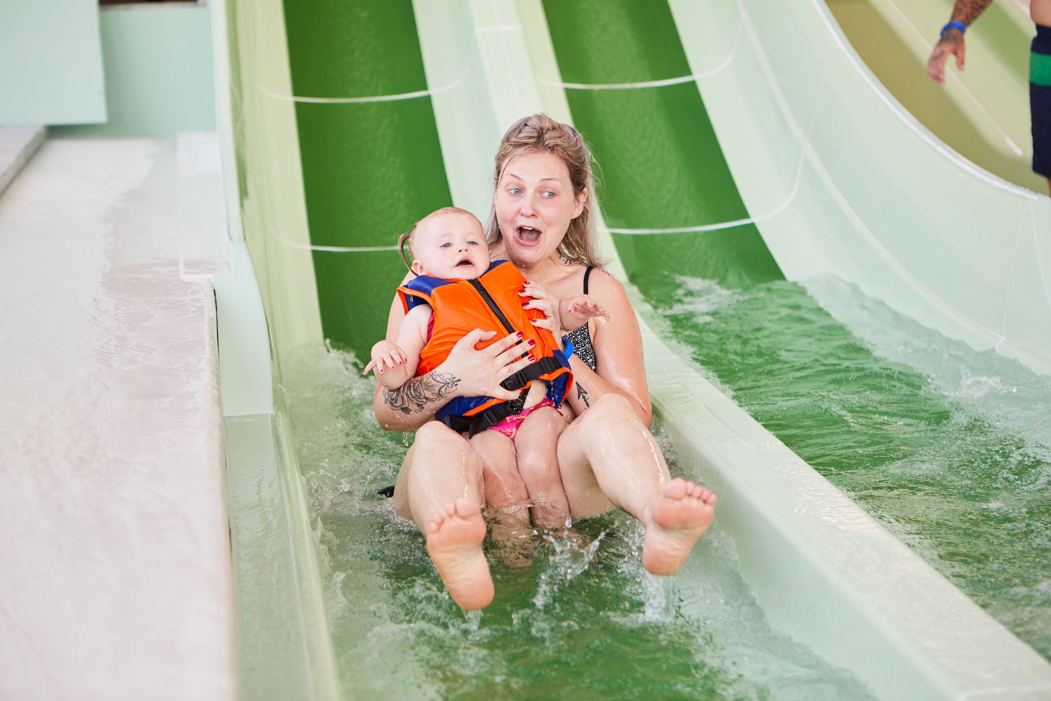 Mama glijdt samen met haar baby van de glijbaan van Bambino Beach.