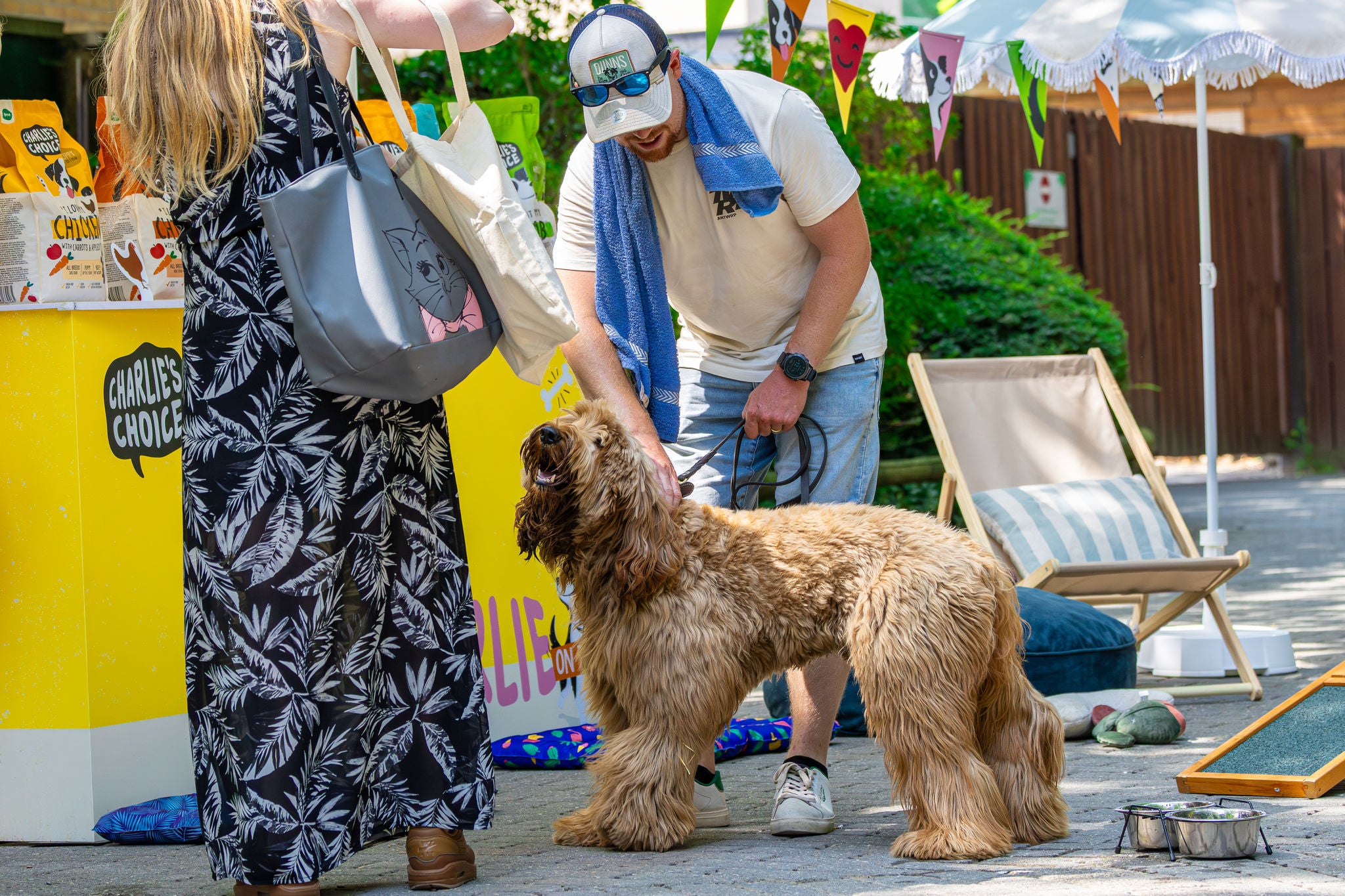 Baasjes staan samen met hun hond aan een stand voor hondenvoeding tijdens Dog Days.